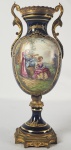 SEVRES - ANFORA EM PORCELANA AZUL COBALTO COM BRONZERIA ORMOLU. A. DECORADA COM CENAS DE GALANTEIO, ARREMATES EM OURO. FRANÇA, INICIO DO SEC. XX. 23 CM DE ALTURA