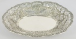 LINDA TRAVESSA PARA SERVIR PÃES EM PRATA ALEMÃ. A BORDA É DECORADA EM FENESTRAS COM RESERVAS CONTENDO FOLGUEDOS DE PUCCI E MAGNIFICAS GUIRLANDAS FLORAIS. TAMBÉM REQUINTADAS RAMAGENS. ALEMANHA, FINAL DO SEC. XIX. 29 CM DE COMPRIMENTO