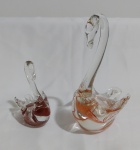 Par de belos Cisnes elaborados em vidro artistico soprado, forjado e repuxado conforme a técnica de Murano italiano, o maior na cor alaranjada medindo 17cm de altura e o menor na cor avermelhada medindo 10cm de altura.
