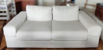 Sofá para 3 lugares, estofado em linhão na cor bege, no estilo moderno. Possui 2 almofadas soltas no encosto e almofadadas presas. Mede 226 cm de comprimento x 94 cm de profundidade do braço e 60 cm de altura.