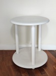 Mesa lateral com 2 estágios no formato circular, 3 colunas no formato cilíndrico, patinada de branco. Mede 50 cm de diâmetro.