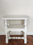 Mesa lateral em madeira, com 2 estágios, sendo o 1º estágio com bordas recortadas e o 2 com forma retilínea, colunas entalhadas, trava central na parte inferior, patinada de branco. O tampo mede 62 cm comprimento x 42 cm de largura, o 2 estágio mede 50 cm de comprimento x 34 cm de largura. Altura total 60 cm.