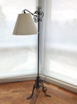 Luminária de chão, em ferro com pé tripóide e braço trabalhados, cúpula em tecido na cor bege. Mede 157 cm de altura.