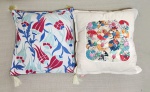 Duas almofadas de estampas diferentes, sendo 1 em algodão cru com 1 face decorada com aplicações de fuxico e a outra em tecido decorado nos tons de azul e vermelho com a segunda face em azul. 40 x 40 cm.