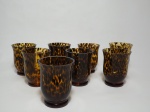 Oito copos em vidro grosso, de origem africana, linha Safari, decorados com marcas da cor âmbar, com pés boleados. Um com quebrado na borda. Alt. 10cm e diâm. 8cm.