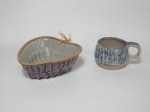 Dois itens em cerâmica vitrificada, sendo 1 caneca com 1 alça medindo  7 cm de altura e 9 cm de diâmetro, no tom de azul e 1 forma medindo 17 cm x 16 cm, nos tons de azul e rosa.