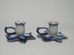 Par de castiçais em porcelana, decorado nos tons de azul e branco, marcado na base Porcelana de Monte Sião - MG. Base no formato de flor. Mede 10 cm x 6 cm de altura.