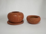 ARTE MARAJOARA - dois cachepots em barro cozido, trabalhados no formato redondo, de tamanhos diferentes, 1 assinado por Raimundo Cardoso, medindo 11 cm de diâmetro (boca)  x 17 cm de altura, acompanha presentoir e o outro assinado por Eurico Leoacacy (Jacó Brasil), medindo 18 cm de diâmetro e 10 cm de altura. (Ambos apresentam bicados na borda).