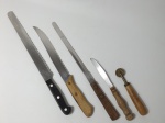 Cinco peças, sendo 3 facas com serras para pão, 1 faca para churrasco e 1 carretinha para moldar massa. A faca maior mede 37 cm de comprimento. (Com marcas de uso).