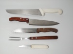 Quatro facas e 1 garfo. A faca maior mede 38 cm de comprimento. Três peças com cabos de madeira e 2 com cabos de plástico rígido na cor branca. Tamanhos diversos. (Com marcas de uso).