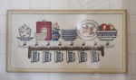 Quadro bordado em ponto de cruz, representando prateleira com utensílios de cozinha. Mede 88 cm x 48 cm.
