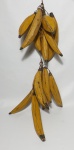 Grande penca de bananas, executada em madeira no formato de bananas da terra, todas maduras. A penca consiste de 17 bananas. Medem as maiores 30 cm.