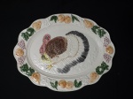 Grande travessa em cerâmica no formato oval, com bordas decoradas com motivos de frutas e desenho de peru no centro, em perfeito estado. Mede 47 cm x 35 cm.