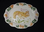 Grande travessa em cerâmica no formato oval, com bordas trabalhadas com motivos de frutas e desenho de lagosta no centro. Mede 47 cm x 36 cm.