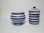 Dois potes em cerâmica, 1 no formato cilíndrico com tampa e 1 cachepot no formato redondo, ambos decorados com faixas nos tons de azul. Medem o cilíndrico 18 cm de altura e o cachepot 14 cm de diâmetro e 13 cm de altura.