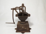Antigo moedor de café em ferro, funcionamento a manivela. Apresenta marcas de ferrugem devido ao tempo. Base quadrada medindo 14 cm x 14 cm. O recipiente onde coloca o café mede 16 cm de diâmetro, altura total 36 cm.