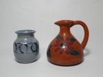 Dois vasos em cerâmica de modelos diferentes, sendo: 1 no bojudo vitrificado decorado com motivo de flores e medindo o bojo 18 cm de diâmetro x 20 cm de altura e 1 menor, vitrificado nos tons de azul claro com faixa decorada. Mede 9 cm de diâmetro x 14 cm de altura.