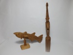 Duas peças em madeira: a) Garfo africano representando figura humana. Costa do Marfim. Comp. 60cm. b) Escultura representando peixe. Comp. 35cm.