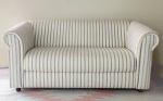 Confortável sofá para 2 lugares, estofado com tecido listrado, medindo 150 cm de comprimento x 80 cm de largura x 75 cm de altura.