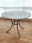 Mesa redonda, estrutura em metal  decorada com cabeças de leão. Tampo em mármore bege Bahia. Alt. 75 x siam. 102cm.