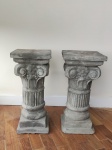 Par de colunas em cimento, estilo greco-romana decorada com flores. Uma com quebrado na base. Alt. 53cm.