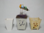 Vasos no formato quadrado, sendo 1 de madeira decorado com motivo de flores, 1 de MDF decorado com flores no formato de coração e 1 em metal decorado com lavandas e pássaros. A maior mede 15 x 12 x 12cm.