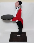 Escultura em madeira, representando um garçom segurando bandeja, a base mede 39 cm x 30 cm. Altura total 80 cm. No estado.