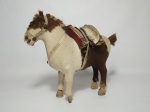 Belíssima escultura representando um cavalo com cela e arreios. Mede 26 cm x 21 cm. (apresenta 1 pata quebrada).
