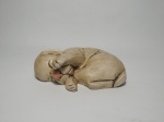 Escultura de madeira, representando 1 cachorrinho deitado dormindo. Mede 25 cm de comprimento.
