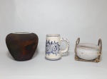Três itens em cerâmica, 1 caneca decorada nos tons de azul e branco medindo 14 cm de altura; 1 cachepot com suporte em fibra de cipó medindo 14 cm x 9 cm e 1 vaso com borda vitrificada craquelada na cor branca, corpo pintado na cor marrom, medindo 18 cm de altura, em formato bojudo.