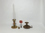 Quatro itens em metal amarelo, 2 porta velas de modelos diferentes, 1 peso para papel e 1 sino. Alt. maior 13cm.