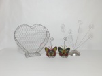 Quatro itens em aramado, sendo: 3 adornos para papel; 1 cesto em formato de coração para colocar objetos e 2 adornos com motivo de borboletas feitos de miçangas, medindo 14 cm de altura. Cesta 20 cm x 24 cm.