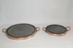 Duas chapas para carnes, pedra sabão com cercadura e alças de cobre. Diams. 34 e 23cm.