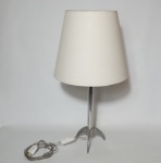 Abajur em metal prateado, pés trípode, haste cilíndrica. Cúpula em tecido branco. Alt. 59cm.