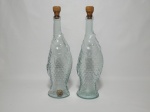 Duas garrafas em vidro moldado e translúcido na forma de peixe, tampas em rolha. Alt. 30cm.