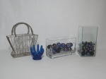 Quatro itens, sendo 2 caixas de vidro com diversas bolas de gude iridescentes. Uma caixa mede 20 x 8 x 12 cm e a outra mede 10 cm x 20 cm; 1 cesta para uso diverso e 1 porta anel para banheiro em silicone na cor azul.