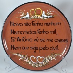 Interessante medalhão decorativo em cerâmica Portuguesa, com inscrição de dito popular. Em perfeito estado, pintado a mão, com gancho para parede, 26 cm de diâmetro.