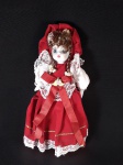 Boneca de coleção com rosto, mãos e pés em porcelana e corpo de pano, adquirida em Coimbra, Década de 1930, vestida em tecido de veludo vermelho com rendas brancas, traje típico de Portugal. Em excelente estado, 25 cm de altura.