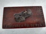 SOUVENIR DA SERRA DOS CARAJÁS, EM BELÉM DO PARÁ, EXIBINDO UMA PEDRA, SOBRE UM PEDESTAL EM MADEIRA DE LEI. MED