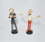 Linda dupla de escultura em resina biscuit representando: - MORTADELO E SALAMINHO - Medida maior: 17 cm de altura x 14 cm x 5 cm de diâmetro de base. Mortadelo e Salaminho são dois atrapalhados agentes secretos da T.I.A (Técnica em Informações Avançadas).