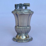 RONSON - `MAYFAIR` -  Antigo isqueiro de mesa em metal espessurado a prata com decorações caneladas e base e topo pontilhados.  Med.: 7,5cm de altura. Apresenta desgastes de uso.