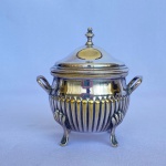 REBOUÇAS - Antigo açucareiro em metal espessurado a prata com corpo canelado, duas pegas laterais e quatro pés. Med.: 10cm de altura e 9,5cm de largura.