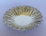 AUREA - Fruteira redonda com bordas recortadas e vazadas em metal espessurado a prata, com cinzelado de flores e folhas e três pés. Med.: 5cm de altura e 23,5cm de diâmetro.