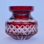 Vaso em cristal doublé na cor rubi com lapidações em formatos geometricos, med. 10cm de altura. Apresenta pequenos bicados na borda.
