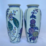 Par de vasos em porcelana branca, decorado com pintura de folhas, frutas e faixas de cor azul. Med.: 20cm de altura e bocal com 7cm de diâmetro.