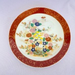 THE ORIENT INC - Antigo prato decorativo de pendurar em porcelana branca japonesa com decorações de flores e borda vermelha. Med.: 16cm de diâmetro.