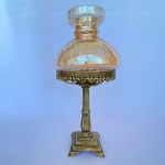 Abajur em metal dourado decorado com volutas e arabescos e com cúpula de vidro na cor de salmão cinzelado de folhas. Med.: 35cm de altura e 17cm de diâmetro. Não possui parte elétrica e apresenta pequena mossa.