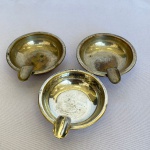 Lote com 3 (três) cinzeiros em metal espessurado a prata com um suporte. Med.: 6,5cm de diâmetro. Apresenta desgastes 