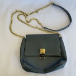 RALPH LAUREN - Bolsa de mão de couro sintético preto com corrente e fechadura em metal dourado. Med.: 16x20cm. Apresenta perdas no couro e marcas de uso.