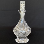 Garrafa de cristal bojuda prensada com desenhos geométricos. Med.: 17cm de altura. Tampa adaptada